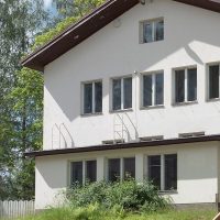 Valkoinen kaksikerroksinen residenssitalo vihreän nurmikon keskellä.